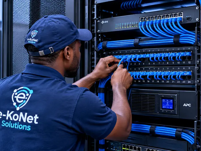 EkoNet technician organising structured cabling and network switches in a server rack